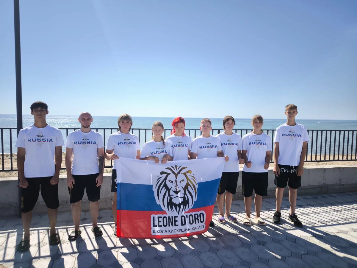 Команда школы с флагом LEONE D’ORO на набережной у моря